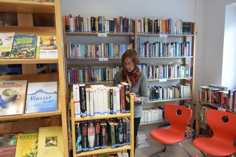 Lesepatin Mia zwischen zwei Bücherregalen