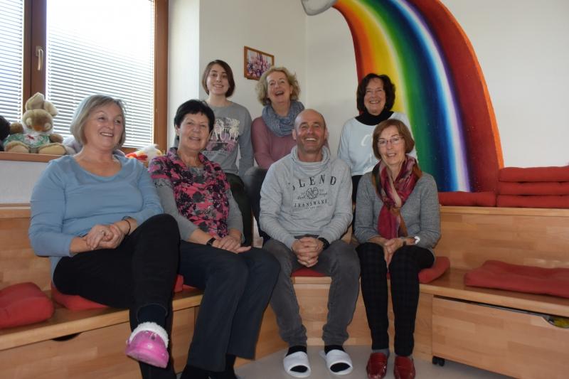 Team: 4 Personen sitzen vorne auf der unteren Holzeckbank und 3 Personen sitzen oben dahinter. 
